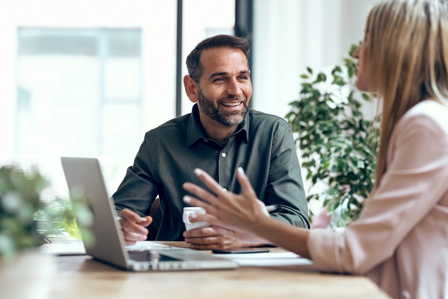 Two colleagues talking across a desk at Xcelentra